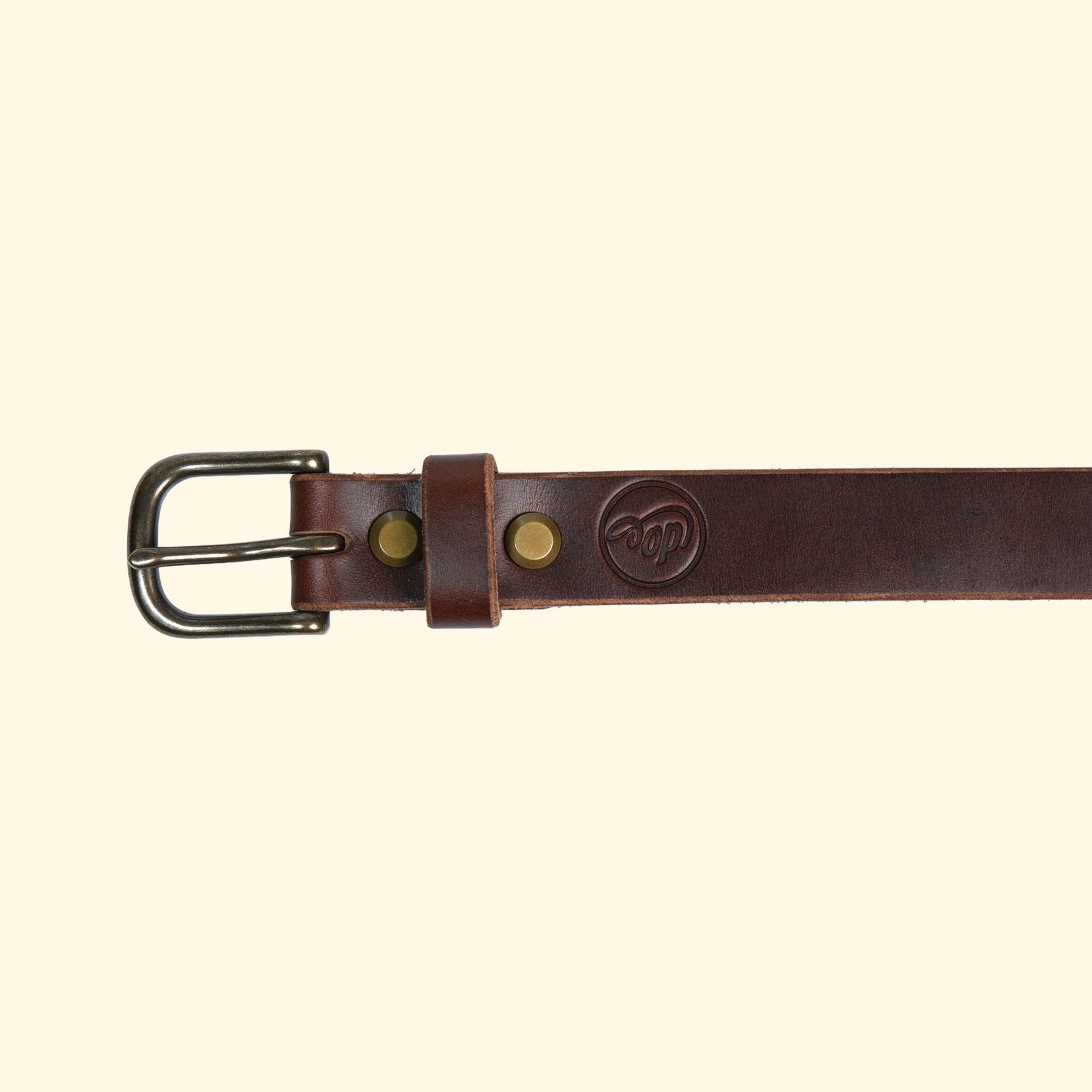 Aussenseite des oldpassion Gürtelmodells op belt slim aus Horween Chromexcel in Dunkelbraun mit antique-farbener Dornschliesse, Lederschlaufe und geprägtem Logo.