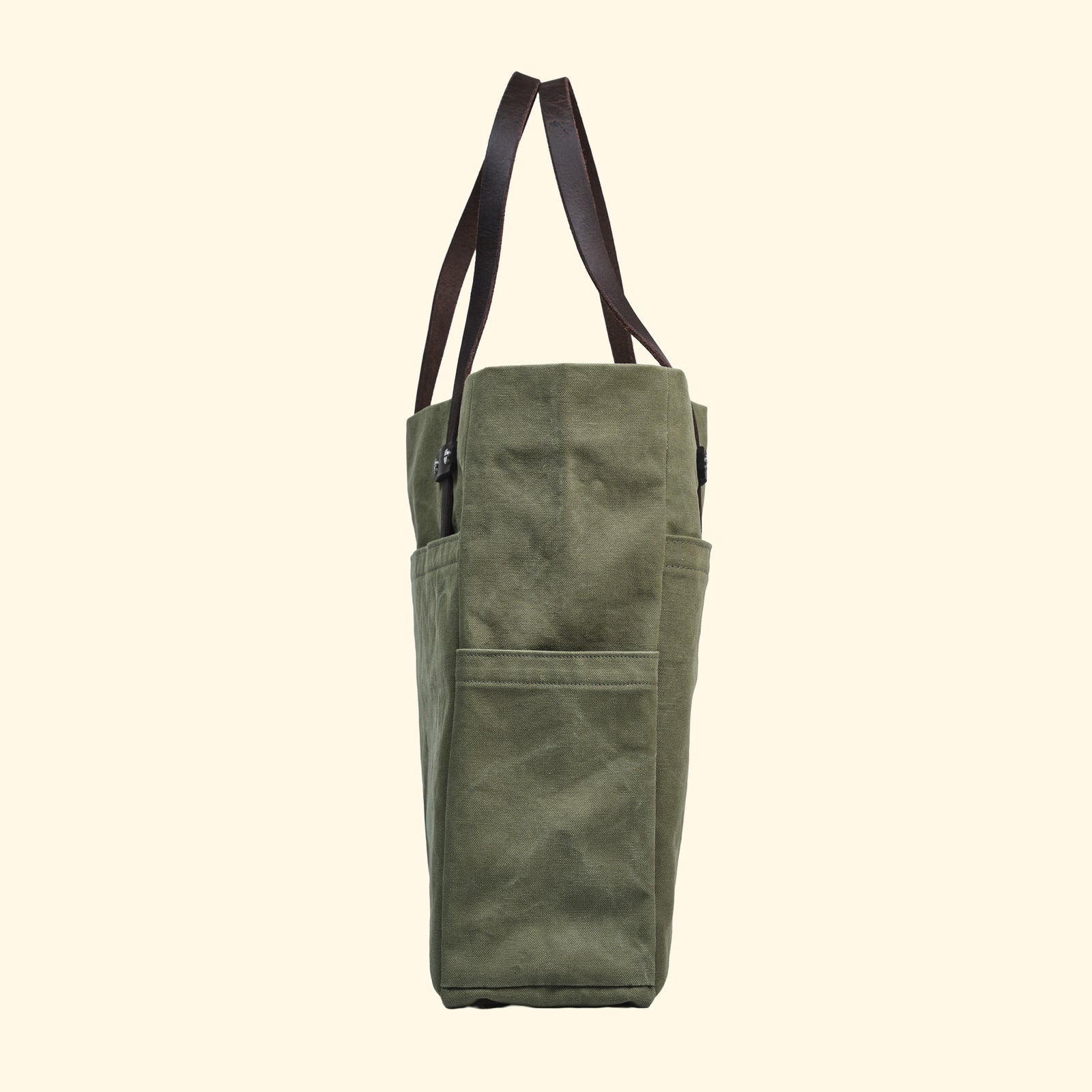 Rechte Seitenansicht der Tote Bag Canvas Olive – seitliche Aussentasche und hochwertige Verarbeitung mit pflanzlich gegerbten Lederhenkeln