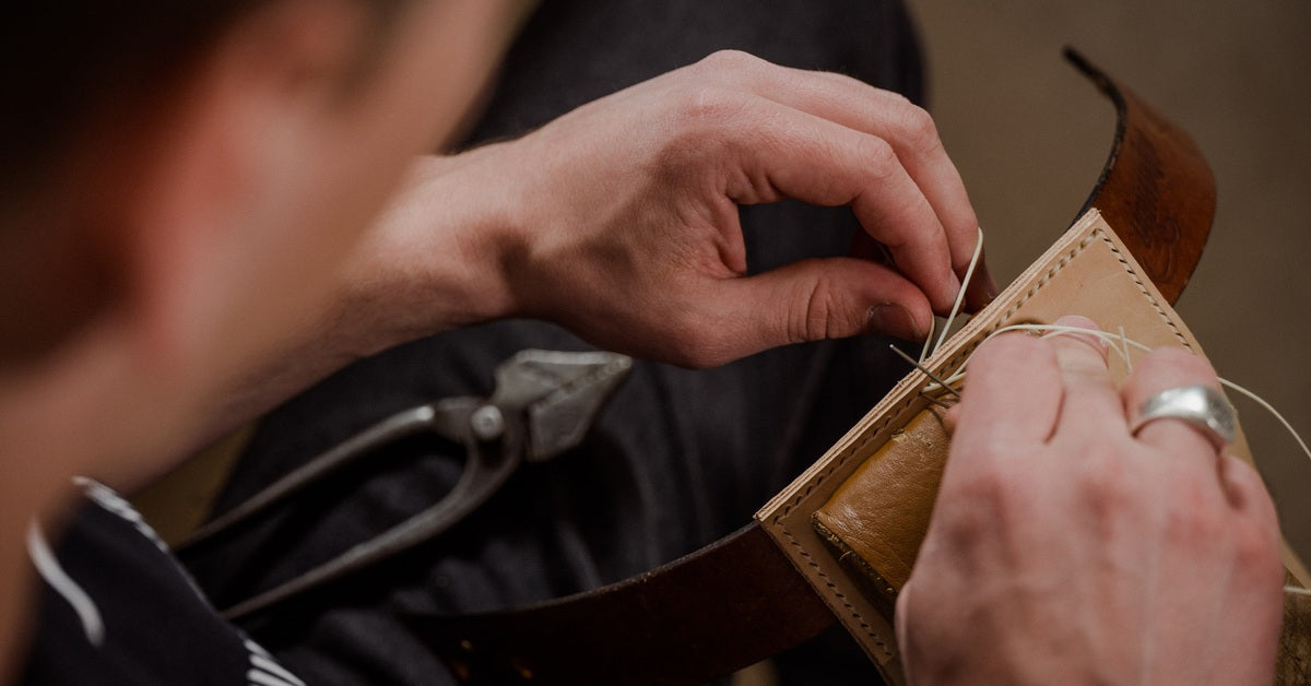 Ledergeldbörse wird von Hand mit Nadel und gewachstem Faden genäht, Detailaufnahme der Handnaht, Thema langlebiges Portemonnaie.