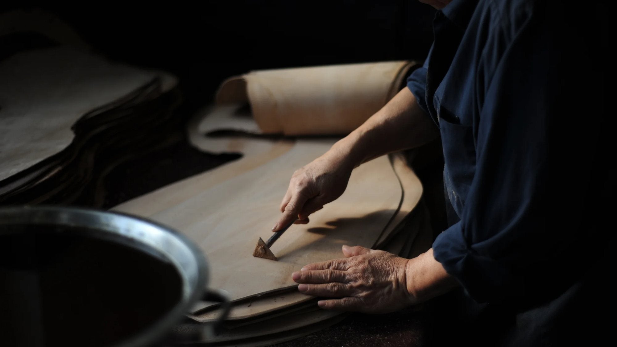 In der Horween-Gerberei in Chicago wird eine Lederhaut von Hand bearbeitet, dunkle Werkstattatmosphäre, Thema Horween Leder.