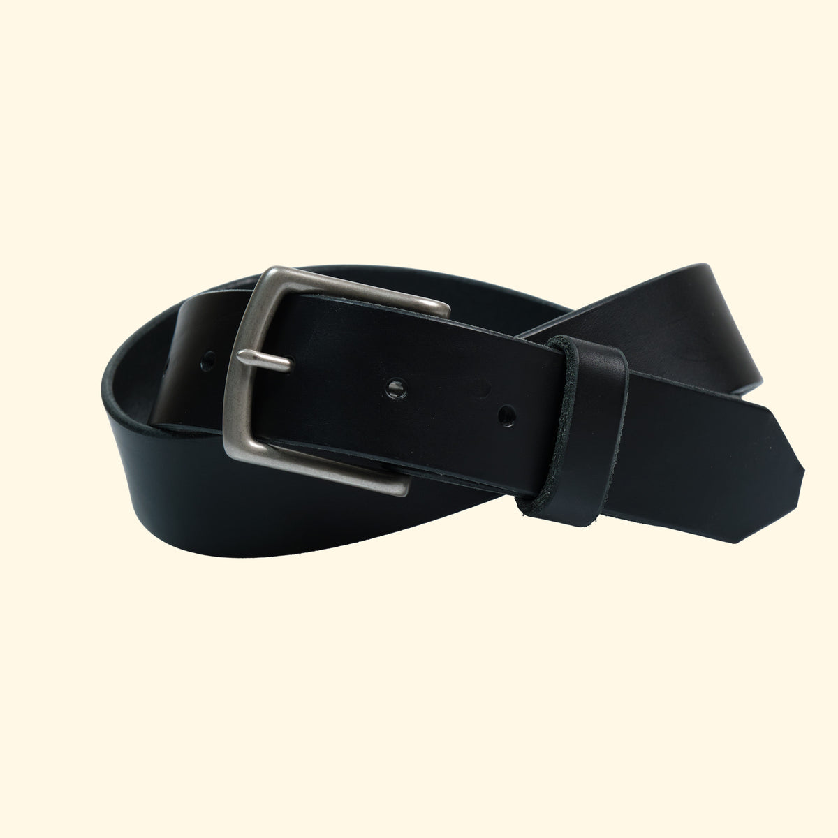 Zusammengerollter op belt aus schwarzem Leder mit silberfarbener Schnalle, handgefertigt in der Schweiz aus vegetabil gegerbtem Rindsleder.