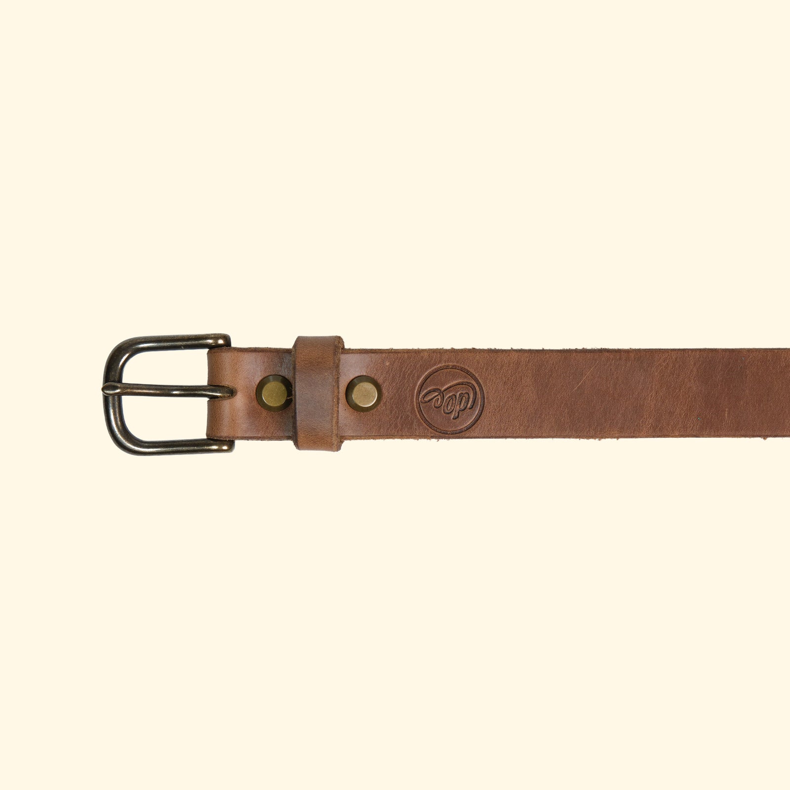 Aussenseite des oldpassion Gürtelmodells op belt slim aus Horween Chromexcel in Natural mit antique-farbener Dornschliesse, Lederschlaufe und Präglogo.