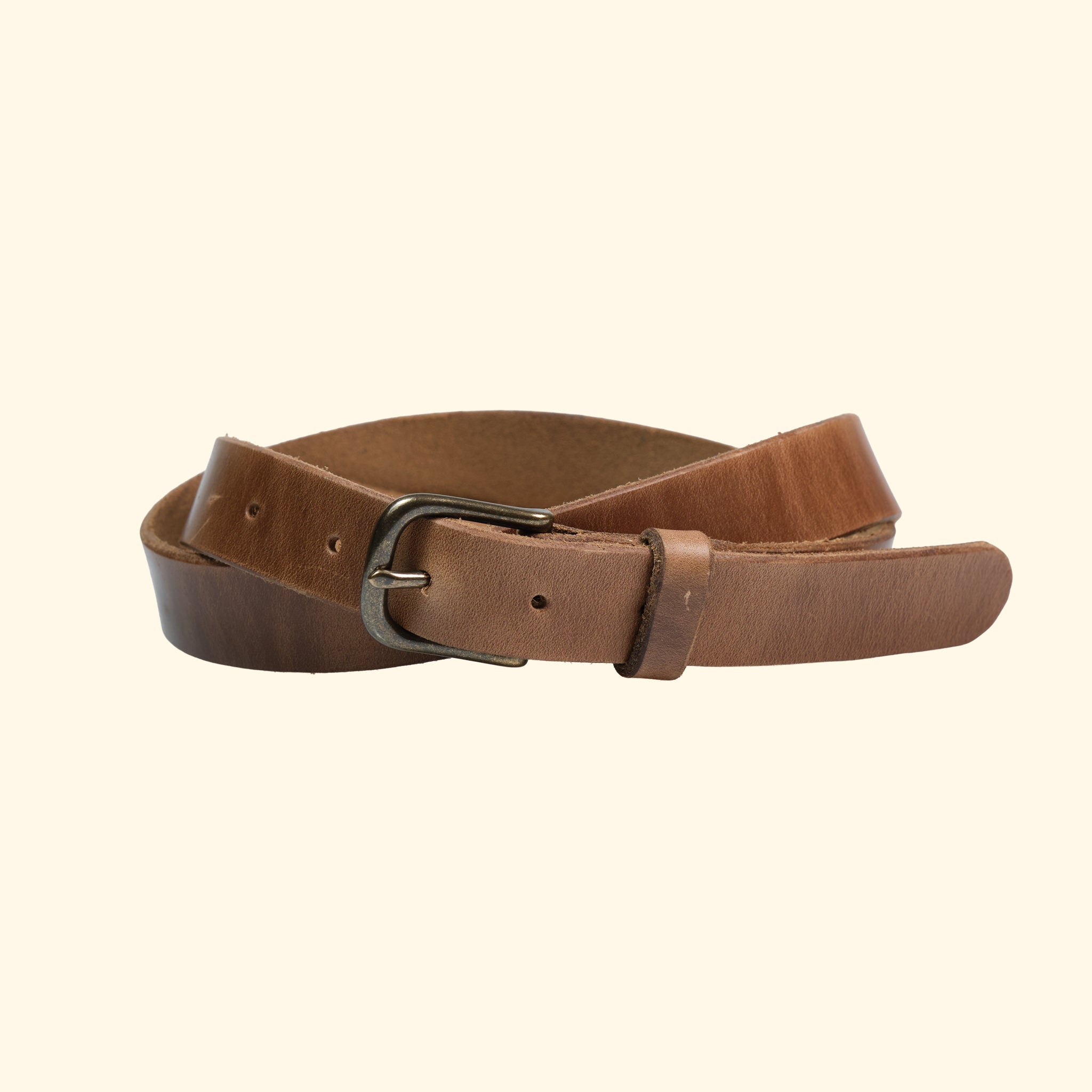 Schmaler Gürtel von oldpassion aus Horween Chromexcel in Natural mit antique-farbener Dornschliesse und Lederschlaufe, leicht gedreht dargestellt.