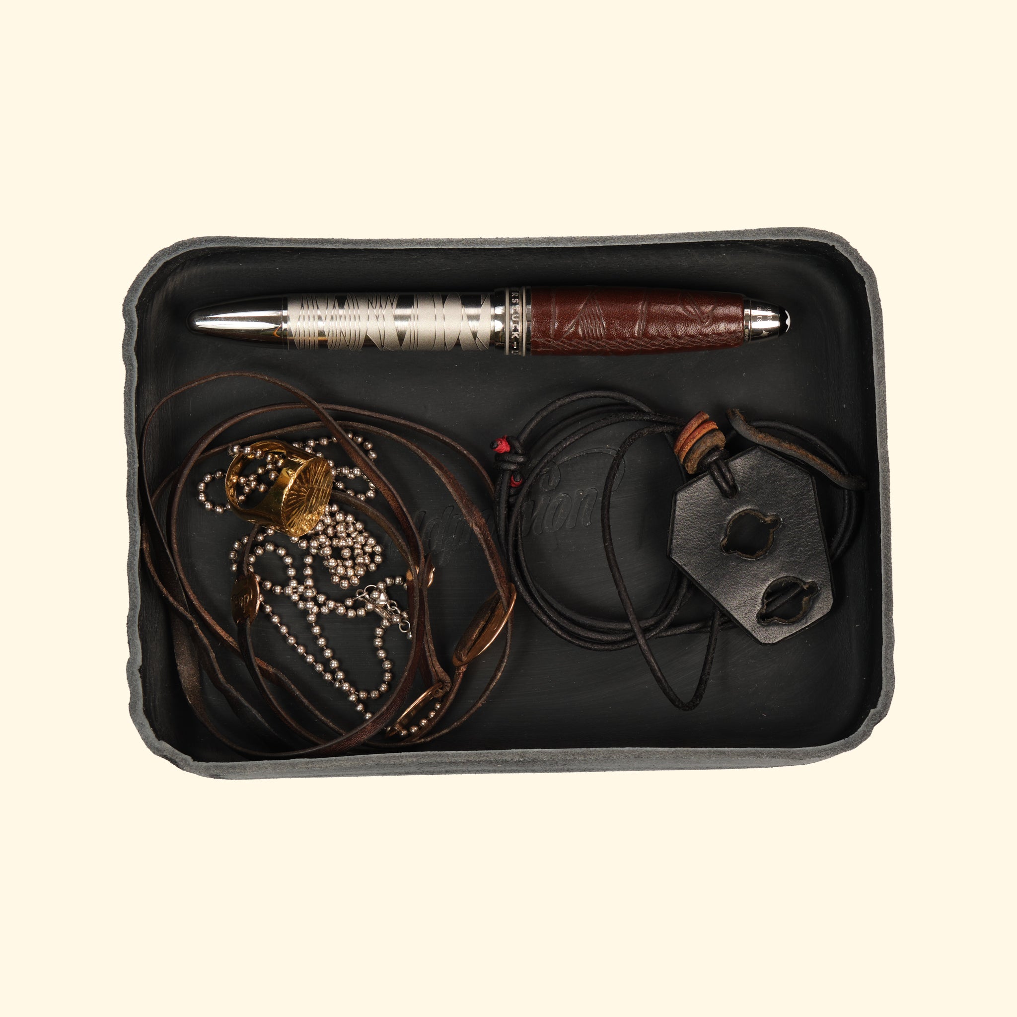 Schwarzes Leder-Tray von oldpassion mit Stift, Ketten und Schmuck zur eleganten Organisation von Alltagsgegenständen.