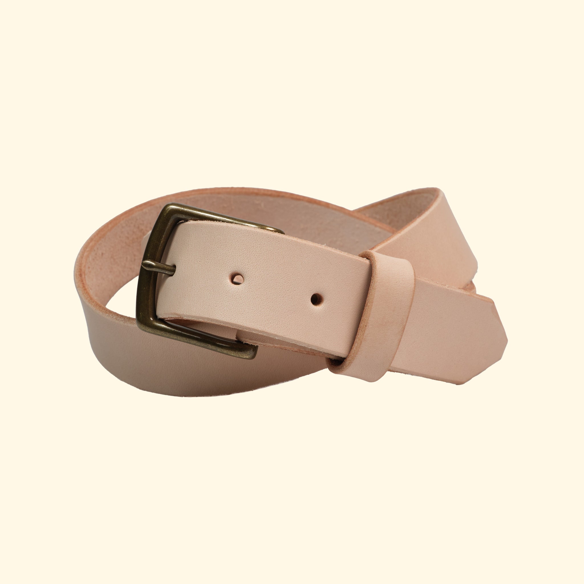 Handgefertigter Ledergürtel aus American Vachetta Leder in Naturfarbe, mit antiker Metallschnalle. Vorderansicht des gerollten Gürtels.
