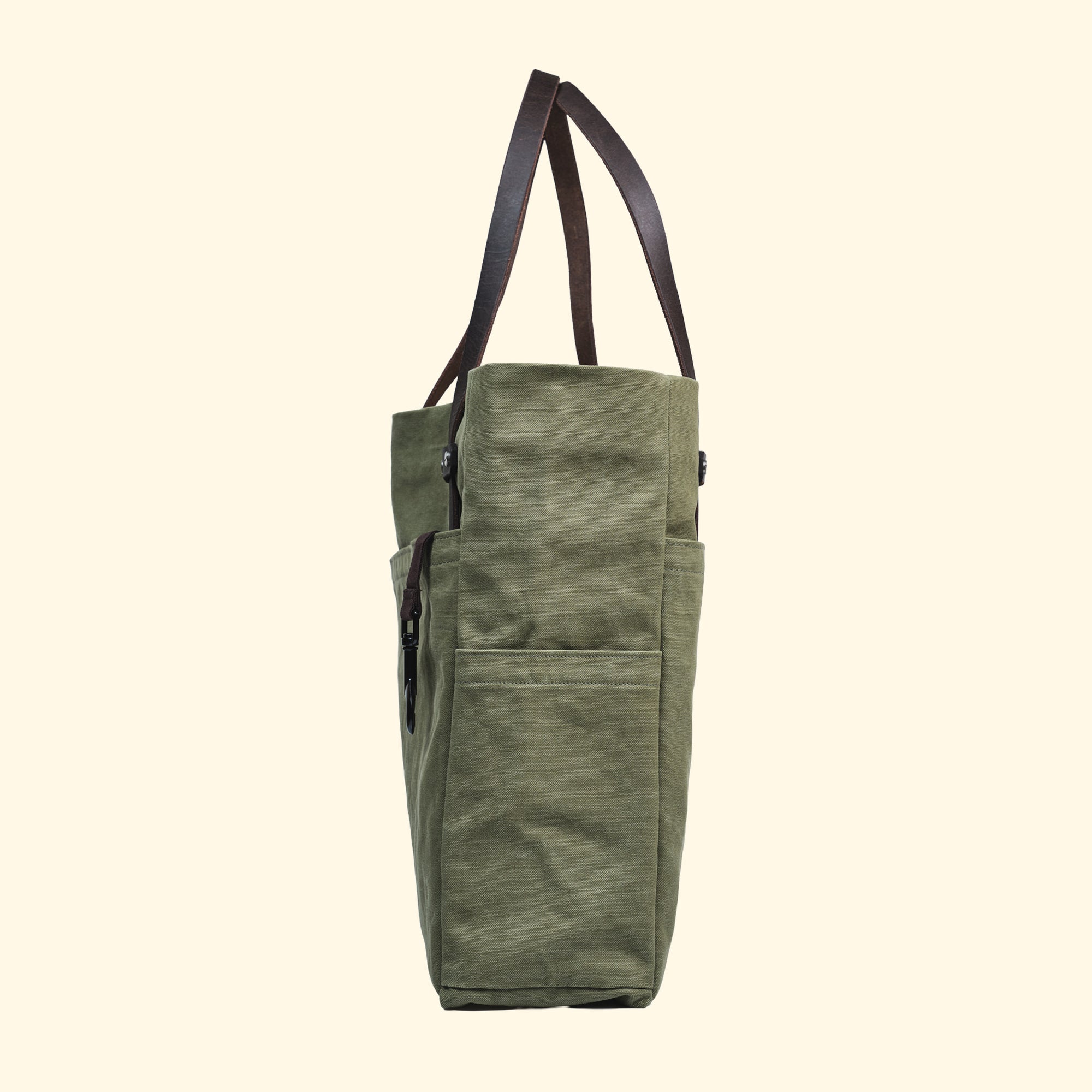 Seitenansicht der Tote Bag aus Canvas in Olivgrün – praktische Aussentasche und robuste Ledergriffe, handgefertigt in der Schweiz